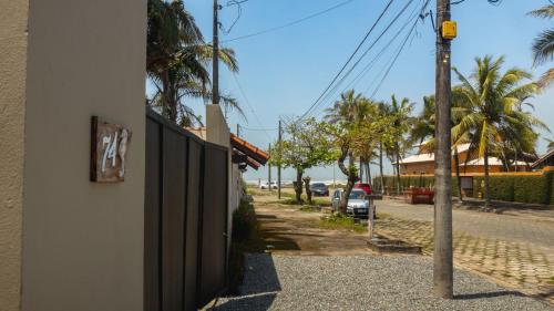 a fence on the side of a street with palm trees at Mundi Studios Peruíbe ( 60 metros do mar) in Peruíbe