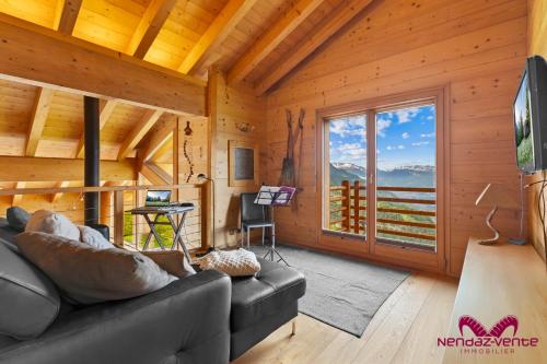 a living room with a couch and a large window at Chalet les Crêtaux in Iserables