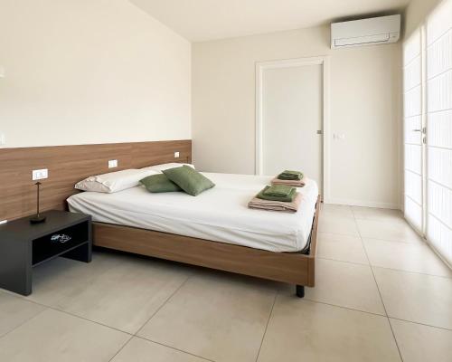 a bedroom with a bed with white sheets and green pillows at Sassimori casa vacanza in Chiampo