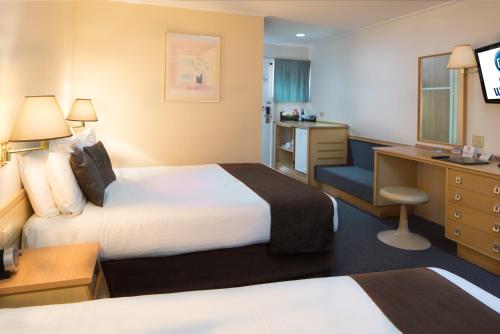 a hotel room with two beds and a desk at Hospitality Geraldton SureStay Collection by Best Western in Geraldton