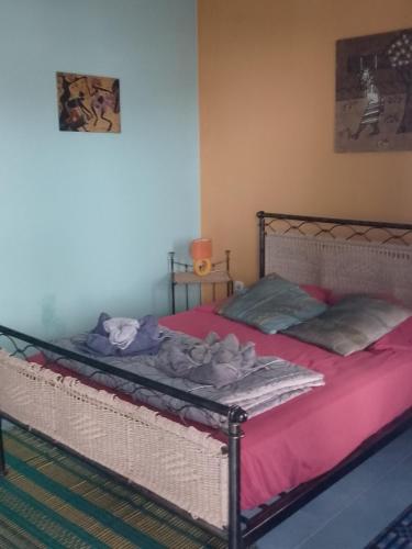 a bedroom with a bed with pink sheets at Djabraba's Rooms in Vila Nova Sintra