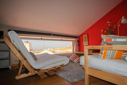 a room with a bed and a chair and a window at Casa do Mar - Familiar T3 Duplex - Terraço - Central in Nazaré