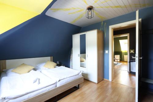 ein Schlafzimmer mit einem Bett mit einer blauen Wand in der Unterkunft Seeblick Hotel-Ferienhaus- Obermaubach in Kreuzau