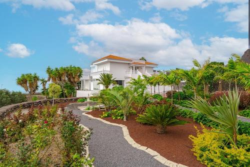 una casa blanca con palmeras y una pasarela en Exclusive villa with ocean and mountain views in San Miguel, en San Miguel de Abona