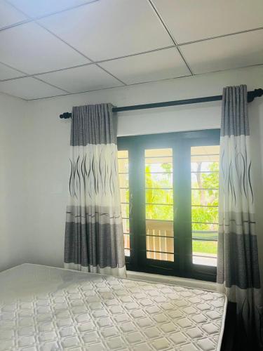 a bedroom with a bed and a window with curtains at Holiday Home Rathnaella in Hassalaka