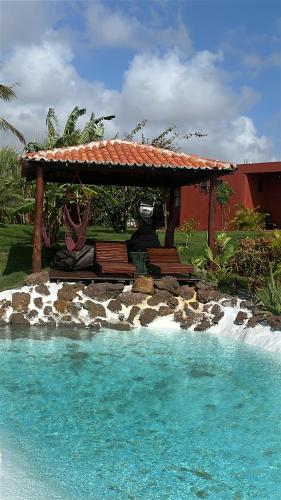 a gazebo with a bench next to a pool at Kitesurf Oasis Maracajaú in Maracajaú