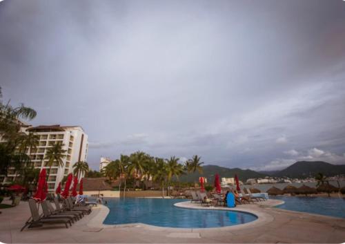 a swimming pool with chairs and umbrellas in a resort at Gorgeous 15 Floor Grand Venetian in Puerto Vallarta