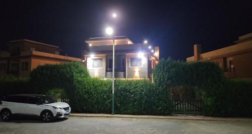 a white car parked in front of a house at night at فيلا مستقلة 5 غرف مطلة على البحر - منتجع بلو باي اسيا السخنة Villa Blue bay Asia Sokhna in Ain Sokhna
