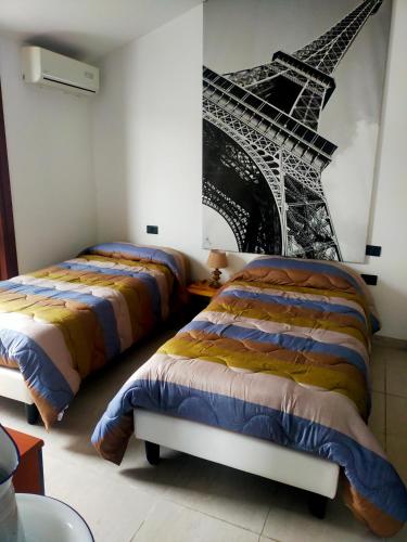 two beds in a room with a picture of the eiffel tower at THE ROOFTOP in Pero