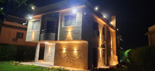 a house with lights on the front of it at night at فيلا مستقلة 5 غرف مطلة على البحر - منتجع بلو باي اسيا السخنة Villa Blue bay Asia Sokhna in Ain Sokhna