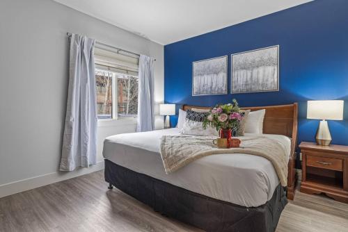 a blue bedroom with a large bed with flowers on it at Spacious 2BR Oasis with Pool and Gym Close to Banff in Canmore