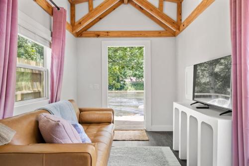 a living room with a couch and a tv at River Run - Riverfront Tiny Home, Trails, and Views! in Sylva