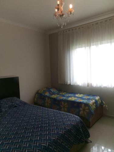 a bedroom with two beds and a chandelier and a window at Tranquilidade e lazer in Piratuba