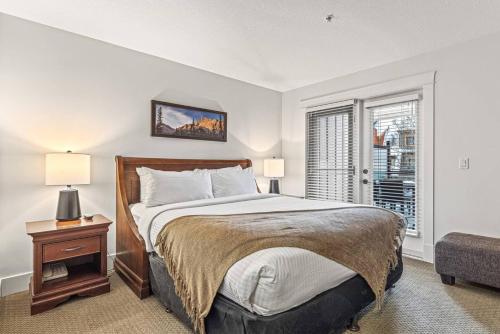 um quarto com uma cama grande e uma janela em Mountain View 2BR Condo with Hot Tub, Pool and Gym em Canmore