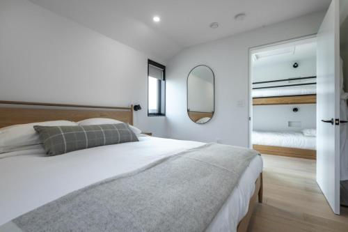 una camera da letto bianca con un letto grande e uno specchio di Cedar - Luxury 2 Bdrm Cottage a Chimney Corner