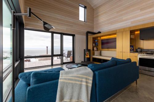 un soggiorno con divano blu e ampie finestre di Cedar - Luxury 2 Bdrm Cottage a Chimney Corner