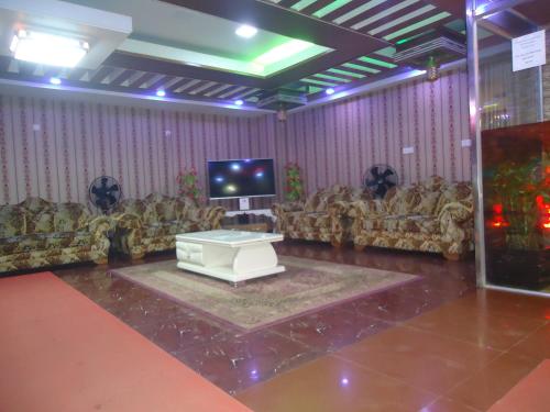 a living room with couches and a tv at Muscat Holiday Resort in Cox's Bazar