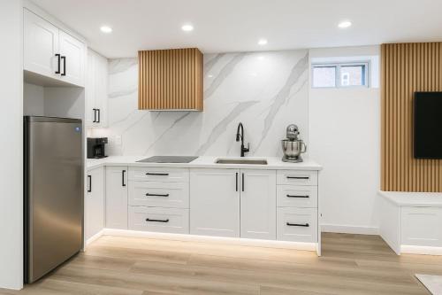 a kitchen with white cabinets and a stainless steel refrigerator at Lux Basement Apartment Getaway in Brampton