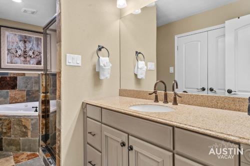 a bathroom with a sink and a mirror at 4BR 5BA Lakeway Retreat w Grill Deck and Tennis Courts by Austin Vacay in The Hills