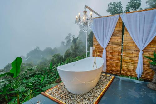 a bath tub on a patio with a view of a forest at Naraview at phuchifa in Thoeng