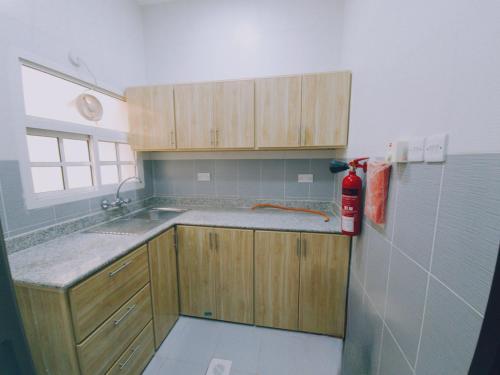 a kitchen with wooden cabinets and a red fire extinguisher at هومي 2 in Salalah