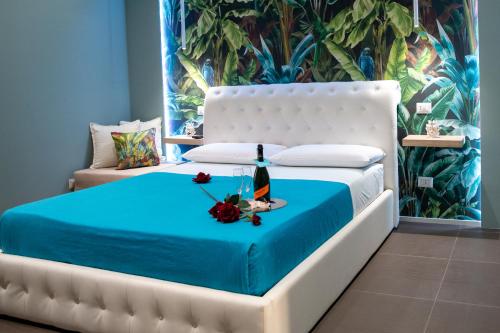 a white bed with a bottle of wine and flowers on it at La casa nel vicolo 3 in Giardini Naxos