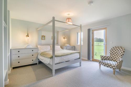 ein Schlafzimmer mit Himmelbett und Sessel in der Unterkunft Beech View 1 in Corsley