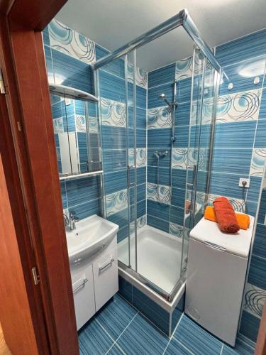 a blue tiled bathroom with a shower and a sink at SimpleStay with parking in Košice