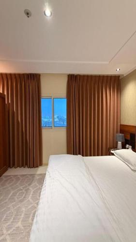 a hotel room with a bed and two windows at نصف القمر للشقق المخدومة in Ḩaql