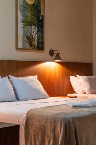 a bedroom with a bed with white pillows and a lamp at Foz Central Budget Hotel in Foz do Iguaçu