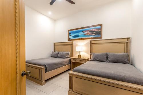 a bedroom with two beds and a night stand with a lamp at Beachfront luxury Condo w Pool in Cabo San Lucas