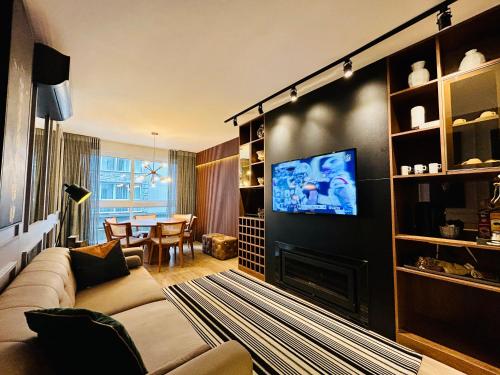 a living room with a couch and a tv at Vita Boulevard Gramado in Gramado