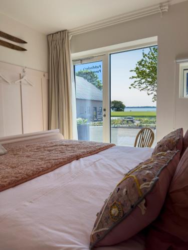 a bedroom with a large bed with a large window at Seaside Retreat & Hotel in Stege