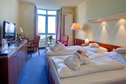 a hotel room with three beds with towels on them at Hotel am Rosengarten in Bad Wimpfen