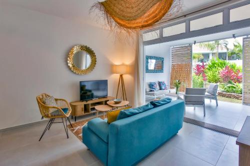 a living room with a blue couch and a tv at Tahiti Beach apartment in Paea
