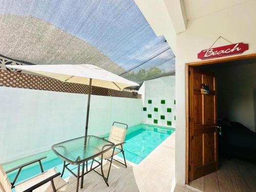 a table with an umbrella next to a swimming pool at Apartamento de playa con piscina privada in Monterrico