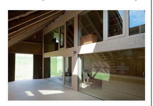 an empty house with glass windows and a chair at Charming duplex in historic farm Fribourg in Bonnefontaine