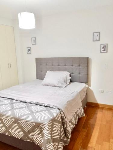 ein Bett in einem weißen Zimmer mit einer weißen Wand in der Unterkunft Amplio y Acogedor, cerca al parque de las aguas in Víctor Larco Herrera