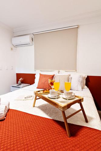 a large bed with a table with two glasses on it at Flat espaçoso, no Manaíra, com varanda ampla, a 100m da praia e ao lado do Mag Shopping in João Pessoa