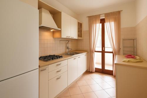 a small kitchen with white cabinets and a window at Villa Carla accesso al mare privato posto auto riservato in Sperlonga