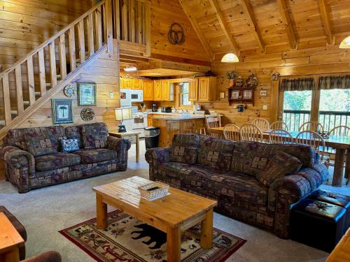 a living room with couches and a table in a cabin at 6BR close to PF Parkway- 2 hot tubs, game room, 4 decks, 3 living areas! in Pigeon Forge