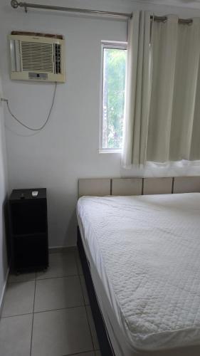 a white bedroom with a bed and a window at Apt Mobiliado despesas inclusas in Marabá