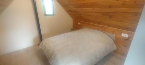a bed in a room with a wooden wall at Maison à 5 min de la plage in Hervelinghen