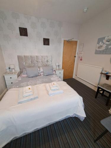 a bedroom with a large white bed with towels on it at The Sandgate in Skegness