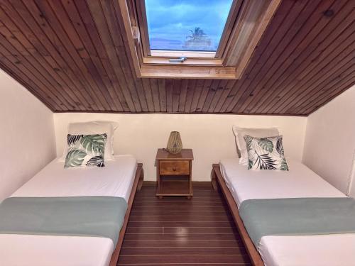 two beds in a room with a window at Le Mohana - L'évasion tropicale de l'Est in Saint-André