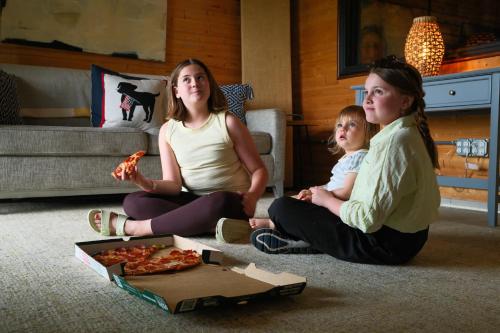 Ashland CityにあるRelaxing Riverfront Family Escape w Private Dockの床に座ってピザを食べている3人の女性のグループ