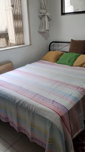 里约热内卢Quarto da Nubia no Coração da Lapa的卧室里一张带条纹毯子的床