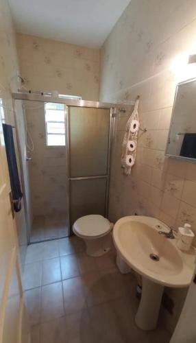 a bathroom with a shower and a toilet and a sink at Casa do Kazu in Águas da Prata