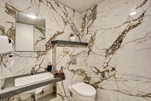 a marble bathroom with a toilet and a sink at Orchid 001Airport view55 TVCoffee maker in Pune