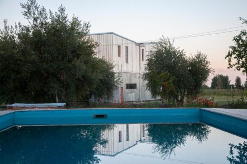 a swimming pool in front of a building with a house at Finca Bravi in Maipú